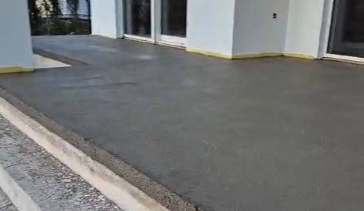 Gotova siva vanjska ploha uz bijeli zid kuće, žuta rubna traka uz zid i stupove